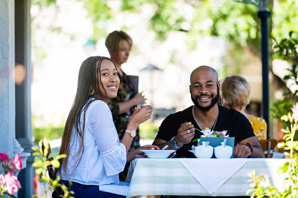 istock Couple on a restaurant veranda having a meal both looking at camera 1205497464