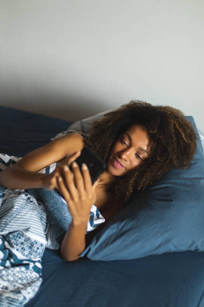 istock Black young woman using phone in the bed 1205498419