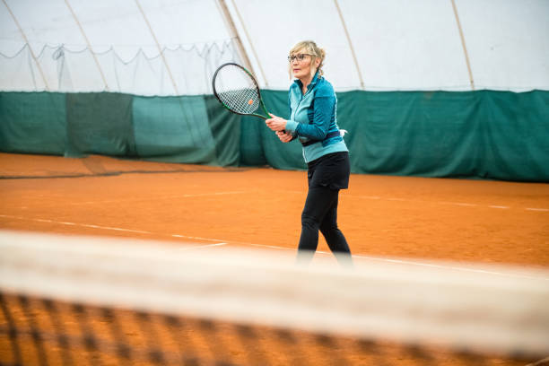 starsza kobieta gra w tenisa - indoor tennis zdjęcia i obrazy z banku zdjęć