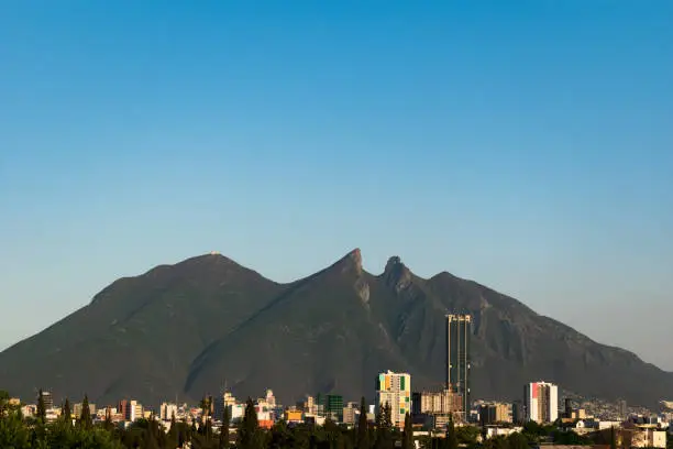 The iconic Cerro de la Silla in the northern Mexican city of Monterrey, on a bright cloudless day. A couple of buildings can be seen on the horizon.