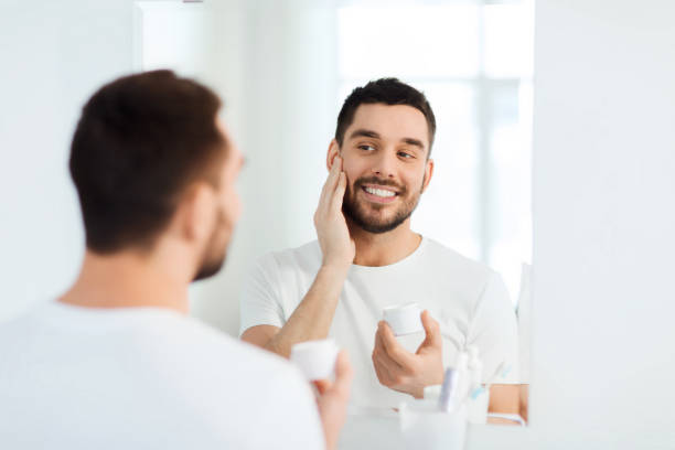 istock happy young man applying cream to face at bathroom 1205500914