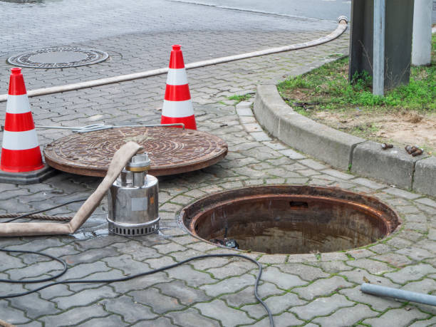 Open sewer with pump and manhole cover stock photo