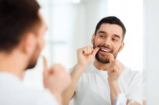 man with dental floss cleaning teeth at bathroom stock photo