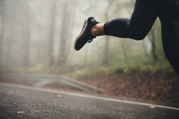 istock Unrecognizable athlete jogging on the road during rainy day. 1205502306