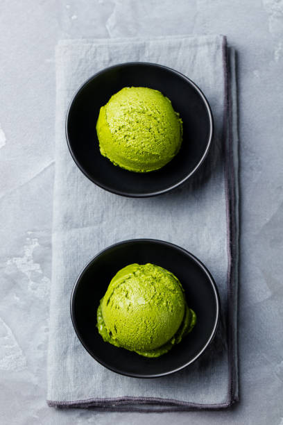 istock Green tea matcha ice cream scoop in bowl on a grey stone background. Top view. 1205503984