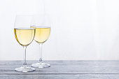 Two glasses with white wine on grey wooden background. Copy space.