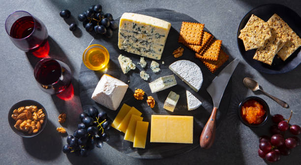 istock Cheese assortment on dark marble cutting board with red wine. Grey background. Top view. 1205504589