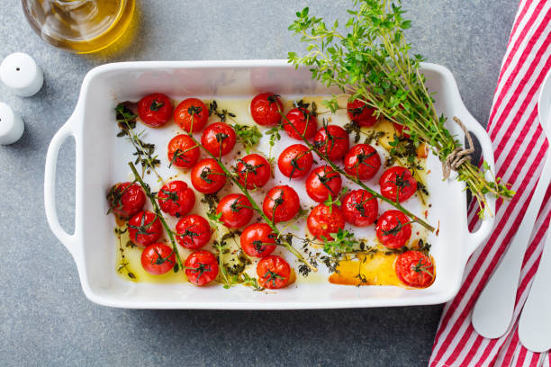 istock Roasted cherry tomatoes with herbs in baking dish. Grey background. Top view. 1205505134