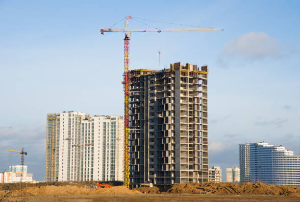 istock Tower cranes working at construction site against blue sky. Crane lifting a concrete bucket. Construction process of the new residential buildings. Transportation blocks and pouring of the cement mix 1205505153