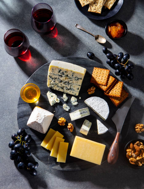 Cheese assortment on marble cutting board with wine. Grey background. Top view.
