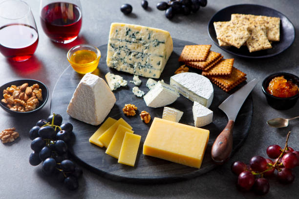 istock Cheese assortment on dark marble cutting board with red wine. Grey background. 1205505277