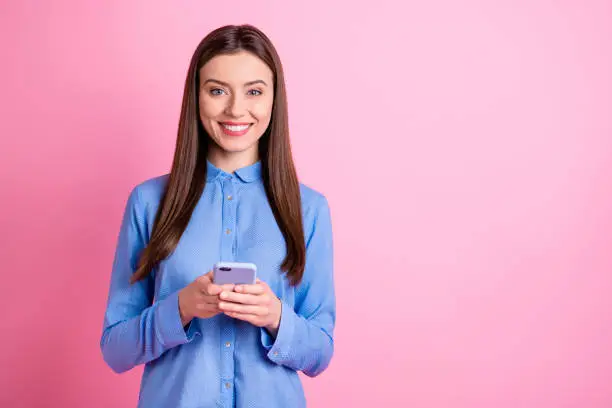 Copyspace photo of cheerful nice attractive beautiful young student holding telephone with hands standing confidently wearing formally, smiling toothily isolated over pink pastel color background