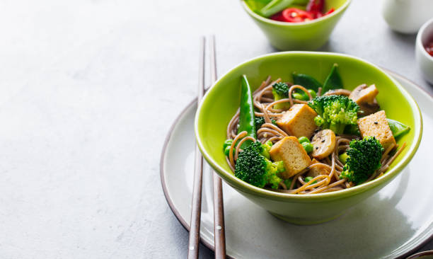 istock Soba noodles with vegetables and fried tofu in a bowl. Copy space. Grey background. 1205507440