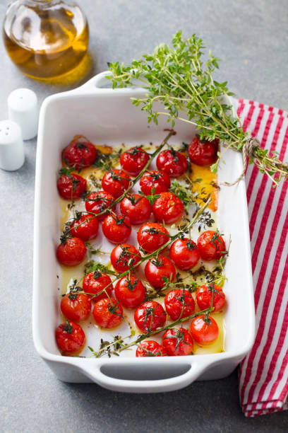 istock Roasted cherry tomatoes with herbs in baking dish. Grey background. 1205507617