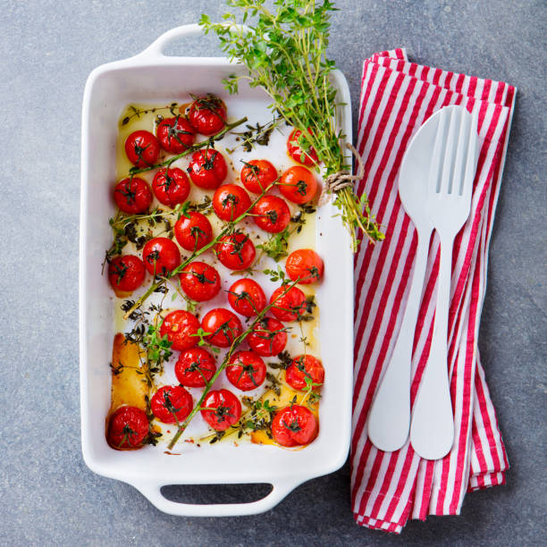 istock Roasted cherry tomatoes with herbs in baking dish. Grey background. Top view. 1205507707