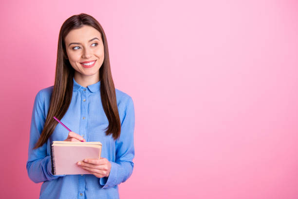 istock Copyspace photo of cute empty space student preparing for exams at university and self developing holding notebook with hands isolated over pink pastel color background 1205508553