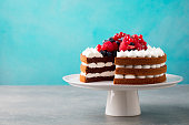 Chocolate cake with whipped cream and fresh berries. Blue background. Copy space.
