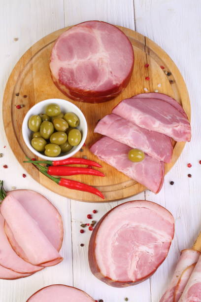 Assorted bacon, ham and olives on a white wooden table