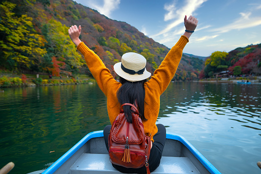 woman traveller tourist enjoy and cheerfully life trip of Japan in river Arashiyama, the famous and popular place for tourist in autumn season change