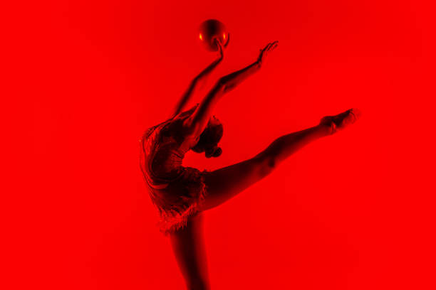 istock Young flexible female gymnast isolated on red studio background 1205510085