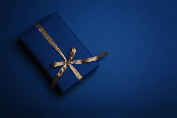 istock Gift box wrapped in classic blue paper with a gold ribbon. 1205511683