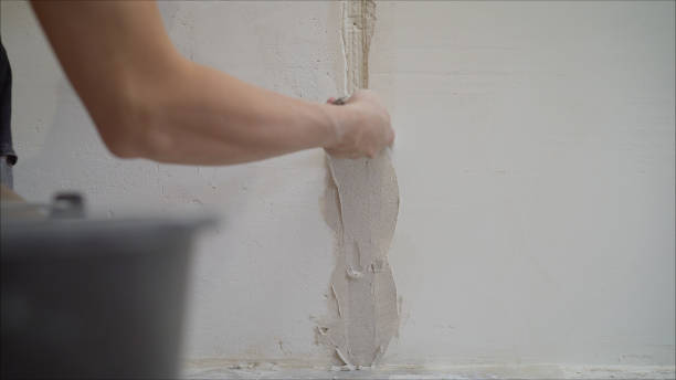 istock Plastering the wall. Hands Plasterer at work. Application of the plaster on the wall. textured plaster 1205512654