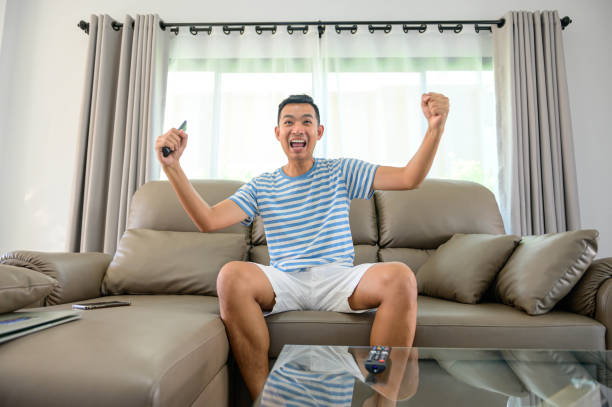 homem assistindo futebol na tv e celebrando a vitória em casa, esportes e entretenimento conceito. - movie time - fotografias e filmes do acervo