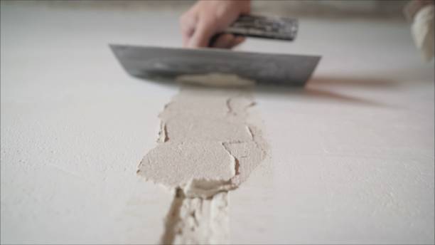 istock Plastering the wall. Hands Plasterer at work. Application of the plaster on the wall. textured plaster 1205513282