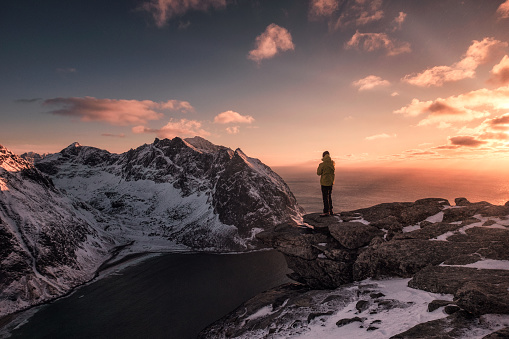 Man traveler standing on top of Ryten mount in sunset at norway