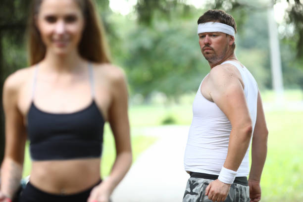 istock Man compares his figure with figure slender girl. 1205528063