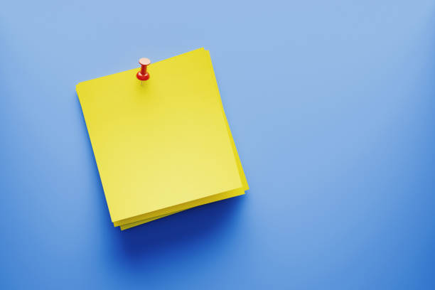 istock Yellow Post It Note Pinned with A Red Pin on Blue Background 1205529446