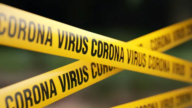 Corona virus tape barrier in front of defocused background. Horizontal composition with selective focus and copy space.