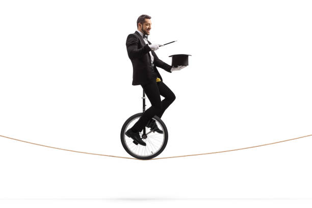 istock Magician holding a wand and a hat and riding a unicycle on a rope 1205535146