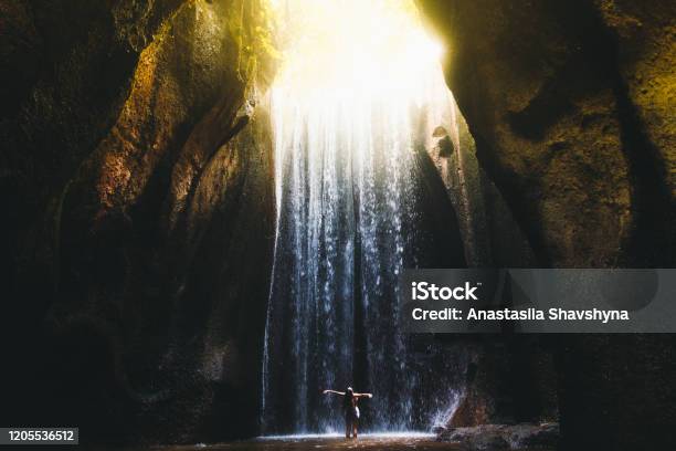 Woman Meets Sunrise In The Cave Under The Big Waterfall On Bali Island Indonesia Stock Photo - Download Image Now