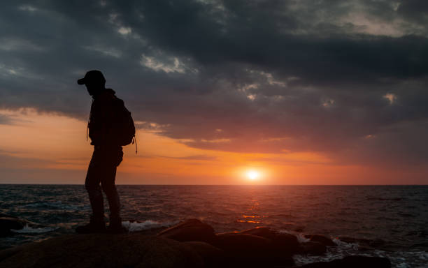 istock Silhouette of backpacker with warm and sunset low lighting. 1205536729