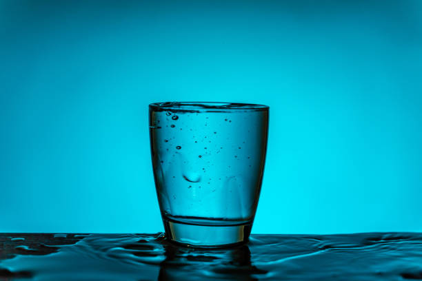 Glass full with water on blue background. The scene is located in a studio environment. The footage is taken with Sony A7III camera