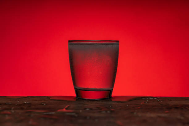 istock Effervescent pill dissolved  into glass of water - red  background 1205537047