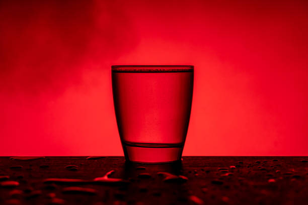 istock Glass with water on wooden table in front red background and smoke 1205537222