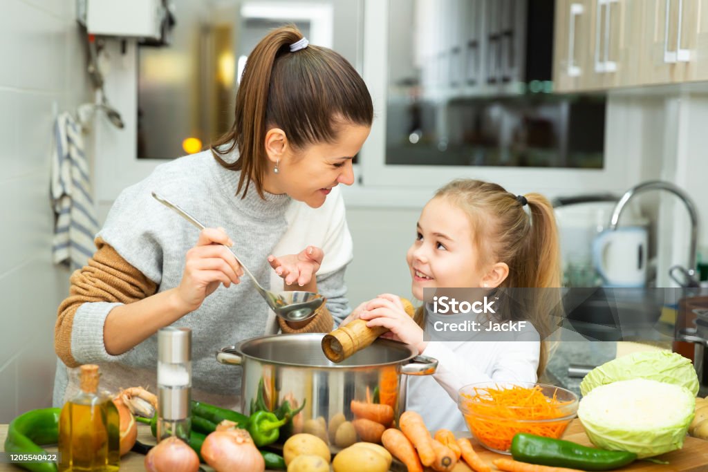Positive Mutter und kleine Tochter schmecken gemeinsam Suppe - Lizenzfrei Familie Stock-Foto