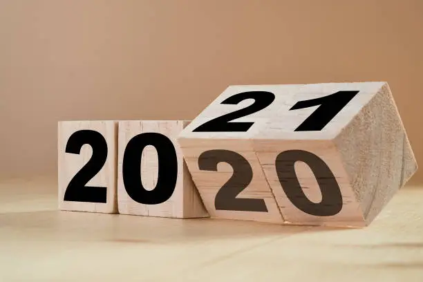 Photo of Flipping wooden cubes for new year change 2020 to 2021. New year change and starting concept.