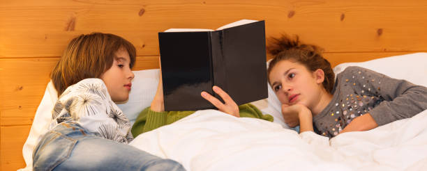 istock Mom and children reading a book together in bed before going to sleep 1205546621