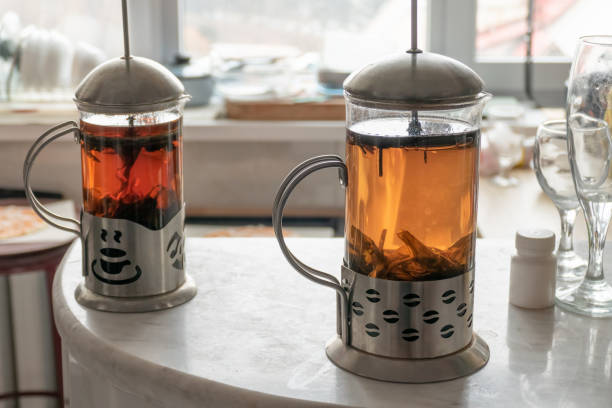 Tea time. Two glass jug with hot large-leaf tea on the marble table in home kitchen