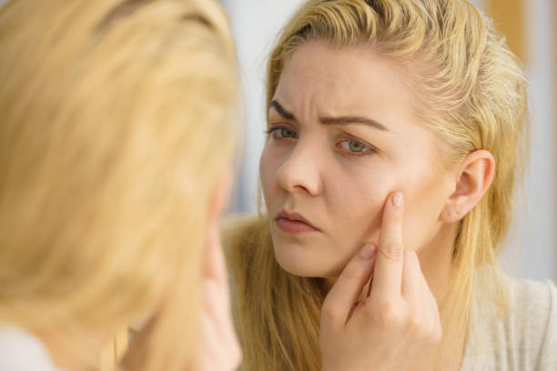 istock Woman looking at her skin in mirror 1205548459