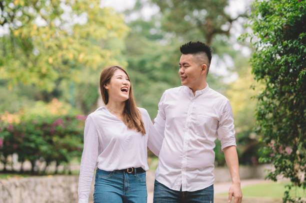 istock an asian chinese couple laughing and talking while walking in the park 1205549865