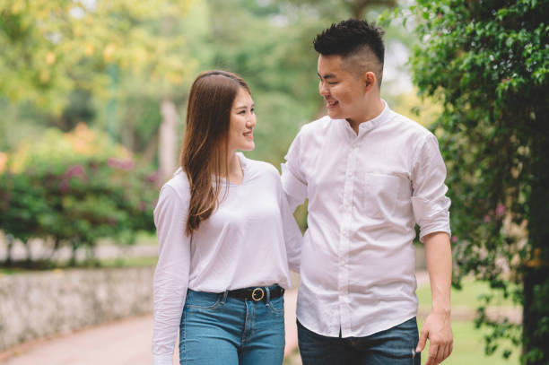 istock an asian chinese couple laughing and talking while walking in the park 1205549918