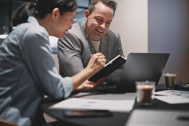istock Two smiling businesspeople discussing notes together at an office table 1205551154