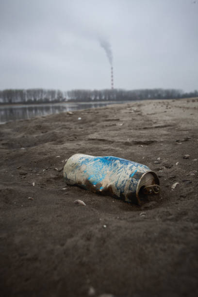 Old dirty plastic bottle overgrown with seashells on a sandy beach after storm. Technogenic pollution of the world ocean. Background with copy space of an environmental disaster