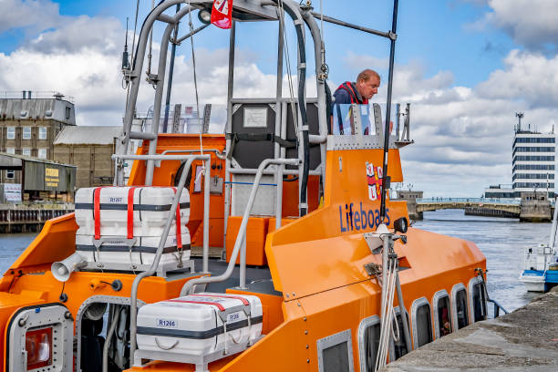 close up of orange rnli inshore lifeboat moored up in yarmouth docks and on display during the annual maritime festival - great yarmouth england norfolk river imagens e fotografias de stock