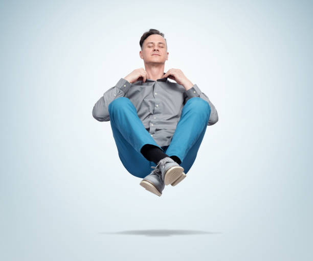 Happy man in casual clothes closing his eyes meditating levitating in the air. Comprehended relaxation Happy man in casual clothes closing his eyes meditating levitating in the air. Comprehended relaxation levitation stock pictures, royalty-free photos & images