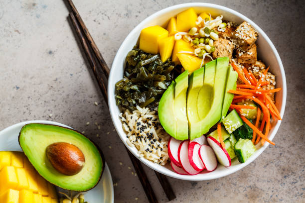 ciotola di poke vegana con avocado, tofu, riso, alghe, carote e mango, vista dall'alto. concetto di cibo vegano. - vegatarian foto e immagini stock